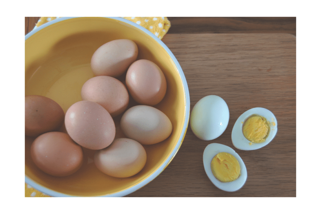 peeled boiled egg halves beside a bowl of boiled eggs