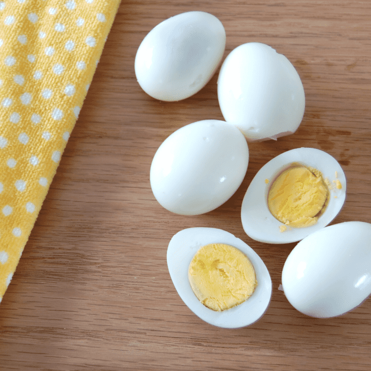 boiled eggs on a cutting board, one cut in half showing yolks