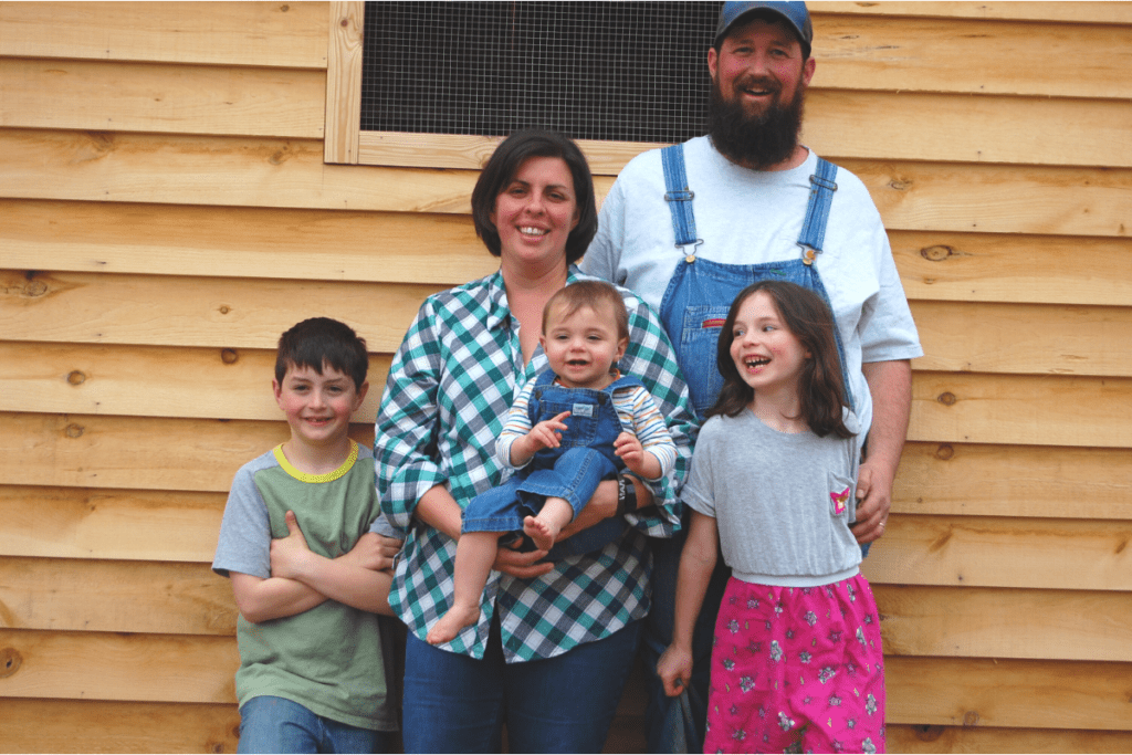 mom, dad, and three kids in front of a chicken coop