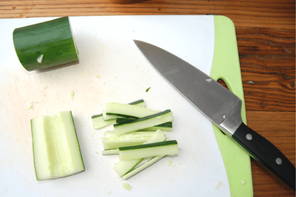 cutting board with a knife and cucumber slices
