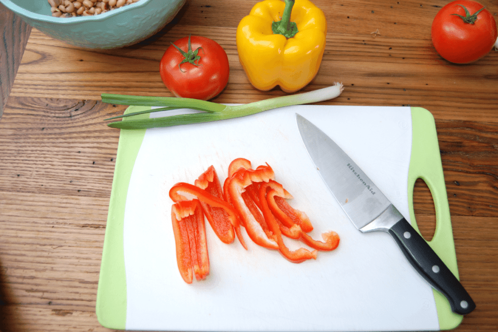 cutting board with a knife peppers cut into strips