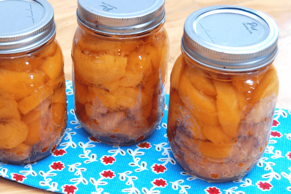3 jars of fresh canned peaches on a blue towel